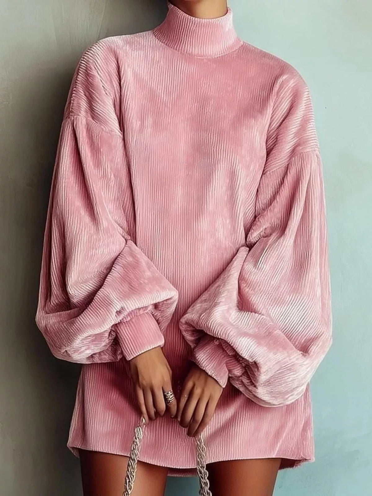 The female model is wearing a pink A-line corduroy turtleneck sweater mini dress with lantern sleeves.